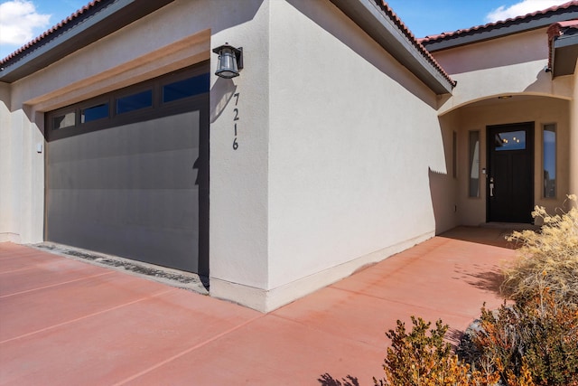 property entrance with a patio, a tile roof, and stucco siding