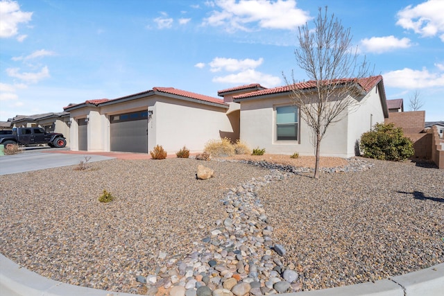 mediterranean / spanish-style house featuring a garage, driveway, a tile roof, and stucco siding