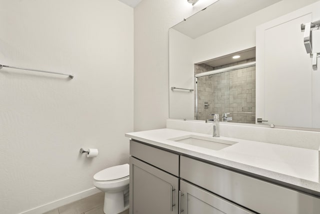 full bath featuring toilet, a tile shower, vanity, baseboards, and tile patterned floors