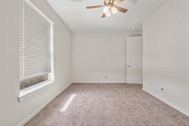 empty room with carpet floors, visible vents, baseboards, and a ceiling fan