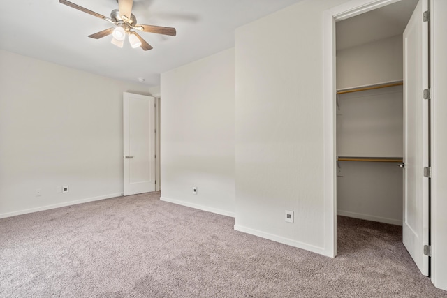 unfurnished bedroom with baseboards, a closet, a walk in closet, and light colored carpet