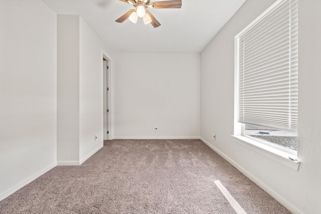 spare room featuring light colored carpet, ceiling fan, and baseboards