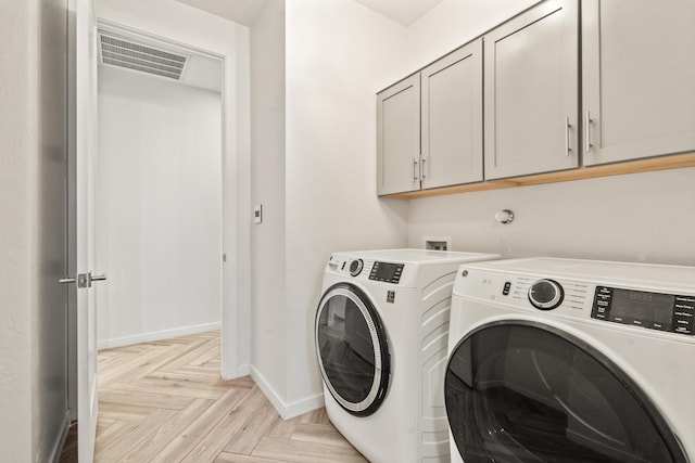 laundry area featuring washer and clothes dryer, cabinet space, visible vents, and baseboards