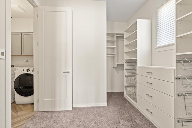 spacious closet featuring washer / dryer and light carpet