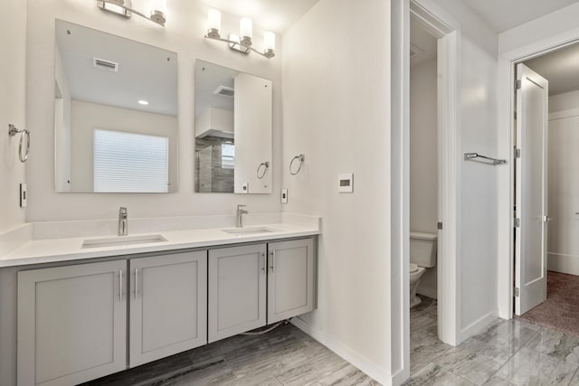 bathroom featuring visible vents, a sink, toilet, and double vanity