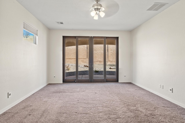 empty room featuring visible vents, a wealth of natural light, and light colored carpet