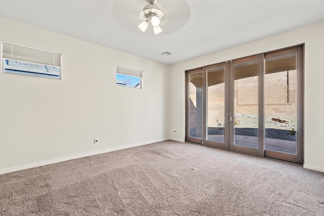 carpeted empty room featuring a ceiling fan, visible vents, and baseboards