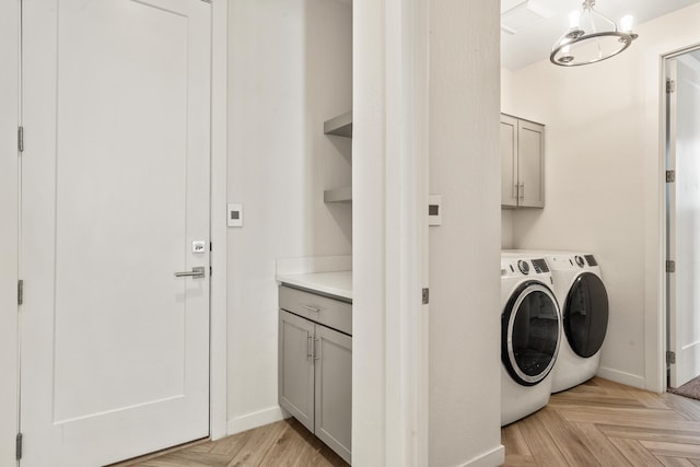 laundry room featuring baseboards, cabinet space, a notable chandelier, and washing machine and clothes dryer