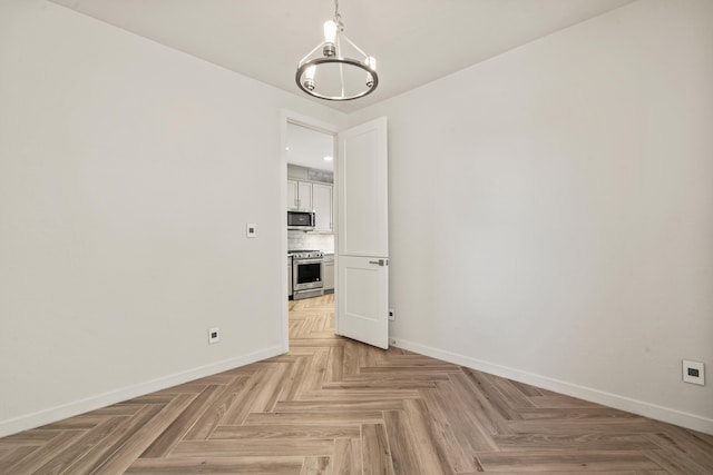 unfurnished dining area featuring a chandelier and baseboards