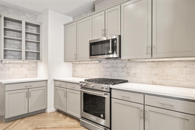 kitchen with tasteful backsplash, gray cabinets, stainless steel appliances, and light countertops