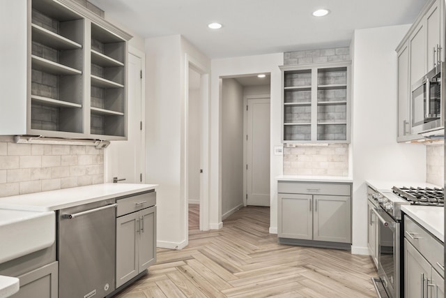 kitchen with open shelves, stainless steel appliances, light countertops, and gray cabinetry