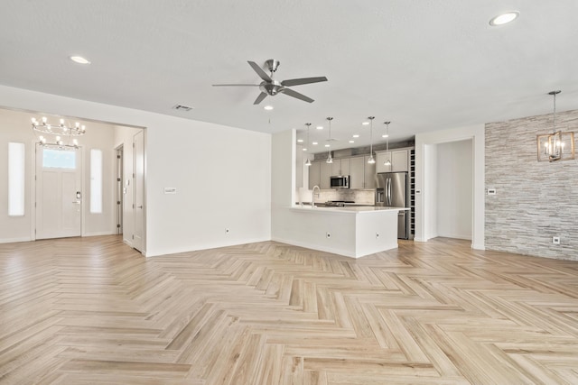 unfurnished living room with recessed lighting, visible vents, a sink, and ceiling fan with notable chandelier