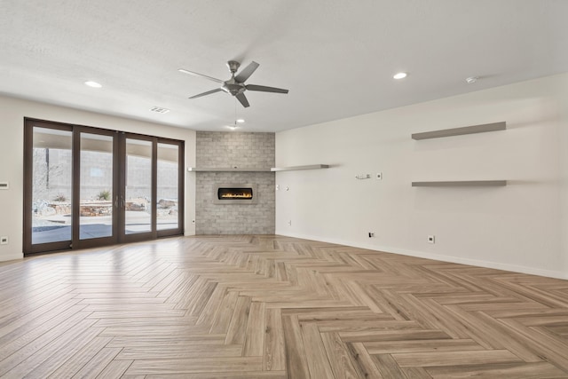 unfurnished living room with a textured ceiling, a brick fireplace, a ceiling fan, and baseboards