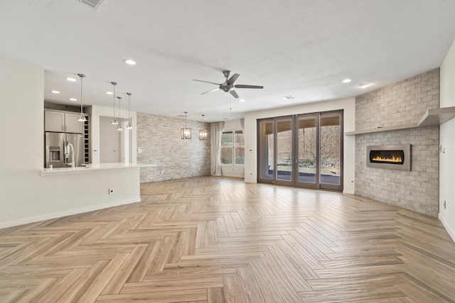 unfurnished living room with recessed lighting, a fireplace, a ceiling fan, baseboards, and french doors