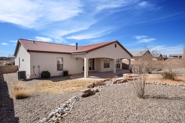 back of house with a tiled roof, fence, central air condition unit, a patio area, and stucco siding