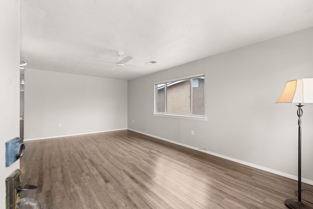 empty room featuring visible vents, ceiling fan, baseboards, and wood finished floors