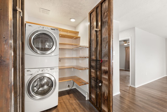 clothes washing area featuring dark wood-style floors, stacked washer / drying machine, laundry area, and a textured ceiling