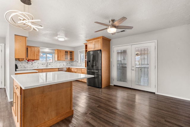 kitchen featuring visible vents, black fridge with ice dispenser, dark wood-type flooring, hanging light fixtures, and light countertops