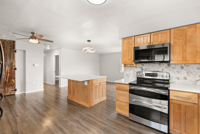 kitchen with appliances with stainless steel finishes, light countertops, a kitchen island, and decorative light fixtures