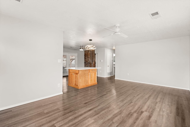 kitchen featuring dark wood-type flooring, visible vents, a ceiling fan, open floor plan, and a center island