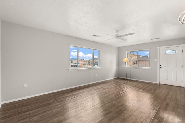 interior space featuring baseboards, a textured ceiling, visible vents, and dark wood-style flooring