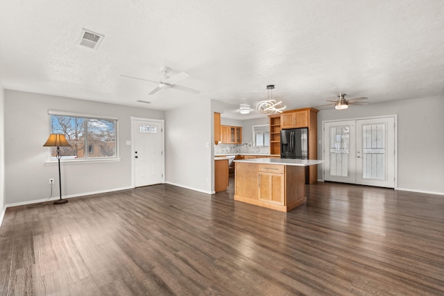 kitchen featuring decorative light fixtures, dark wood finished floors, open shelves, light countertops, and black fridge with ice dispenser