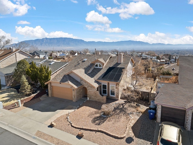 view of front of house featuring a residential view, roof mounted solar panels, a mountain view, and driveway