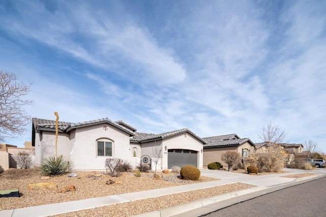 mediterranean / spanish-style house featuring a garage, solar panels, driveway, a tiled roof, and stucco siding