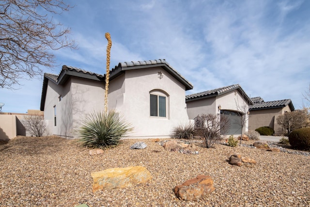 view of front of home with a tiled roof, an attached garage, and stucco siding