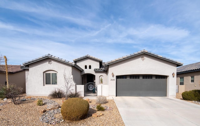 mediterranean / spanish-style house featuring driveway, an attached garage, a gate, and stucco siding