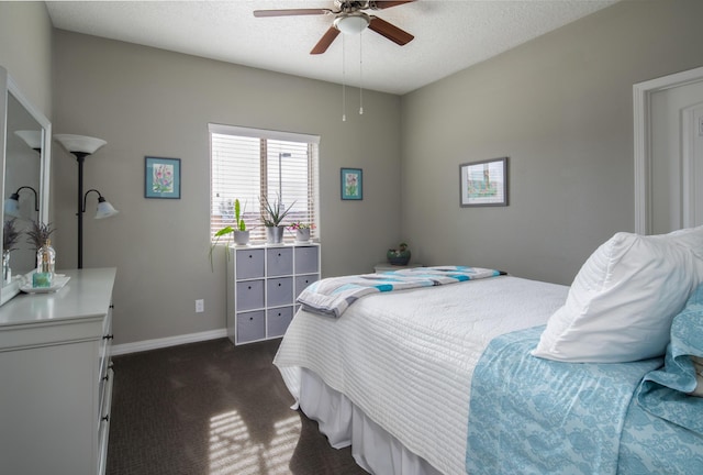 bedroom with a ceiling fan, dark carpet, a textured ceiling, and baseboards