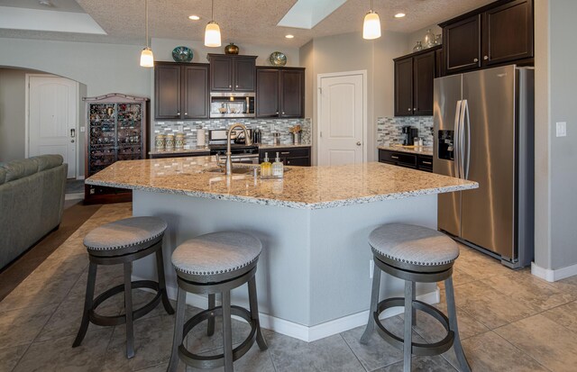 kitchen with dark brown cabinetry, a skylight, arched walkways, and stainless steel appliances