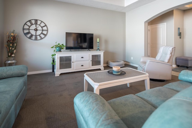 living area with arched walkways, dark colored carpet, and baseboards