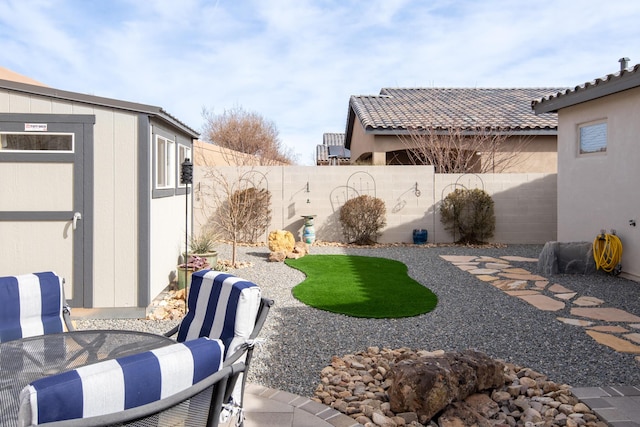 view of yard featuring a patio area, a fenced backyard, a shed, and an outbuilding