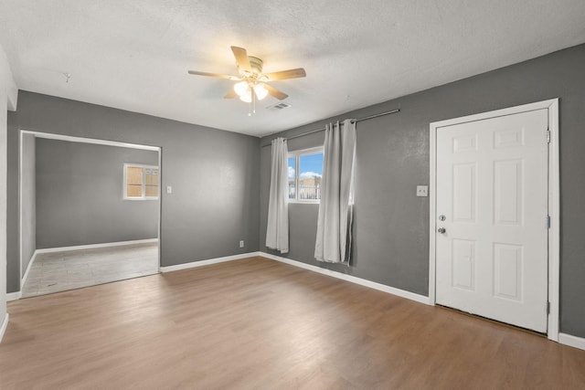 unfurnished room featuring visible vents, ceiling fan, a textured ceiling, and wood finished floors