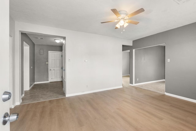 spare room featuring a ceiling fan, baseboards, and wood finished floors