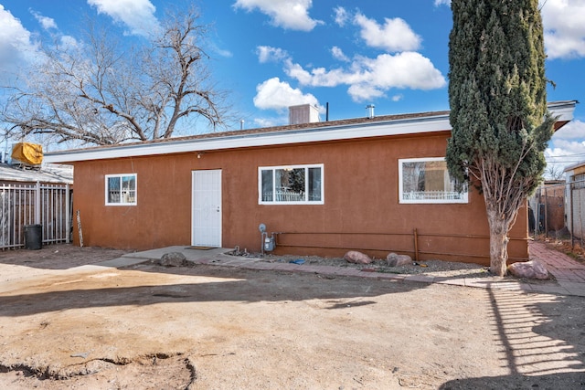 exterior space with a chimney, fence, and stucco siding