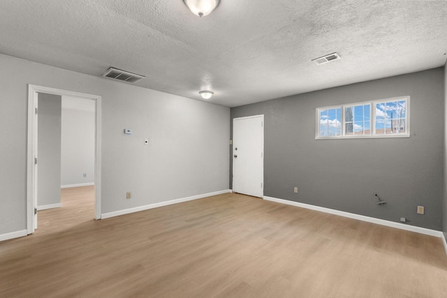 empty room with light wood-type flooring, visible vents, and baseboards