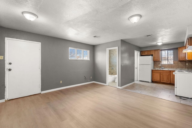 kitchen with white appliances, visible vents, open floor plan, light countertops, and brown cabinetry