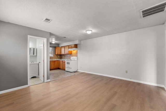 unfurnished living room with light wood-type flooring, baseboards, and visible vents