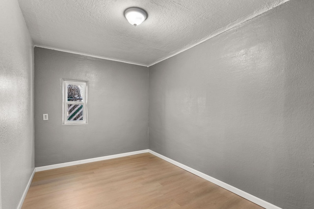 unfurnished room featuring a textured wall, a textured ceiling, baseboards, and wood finished floors