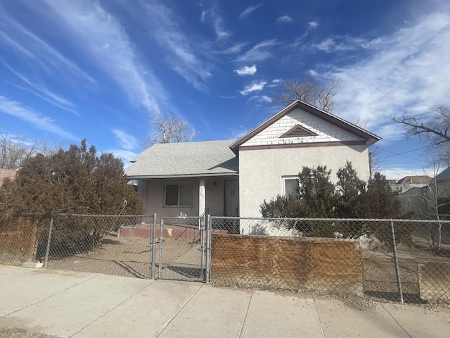 view of front of home featuring roof with shingles, a fenced front yard, a gate, and stucco siding