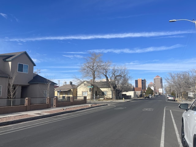 view of road featuring sidewalks, curbs, a city view, and street lights