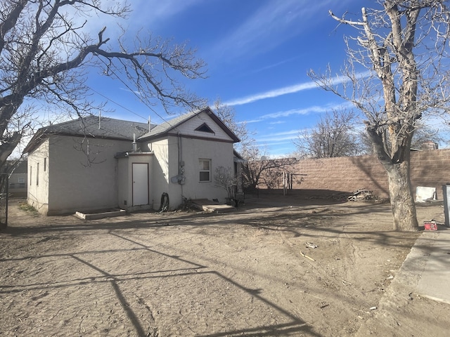 exterior space featuring roof with shingles, fence, and stucco siding