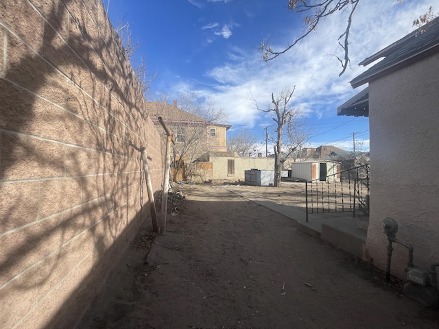 view of yard featuring a storage unit, an outdoor structure, and fence