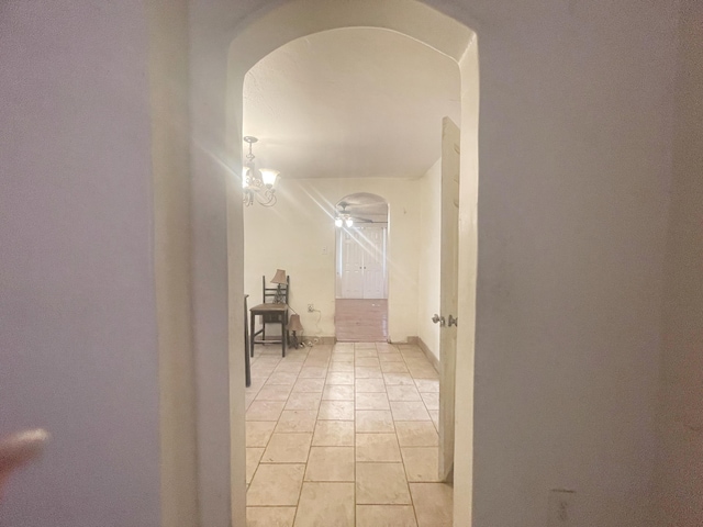 corridor featuring arched walkways and a chandelier