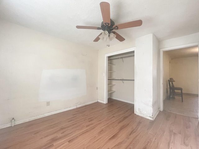 unfurnished bedroom with a closet, ceiling fan, a textured ceiling, wood finished floors, and baseboards