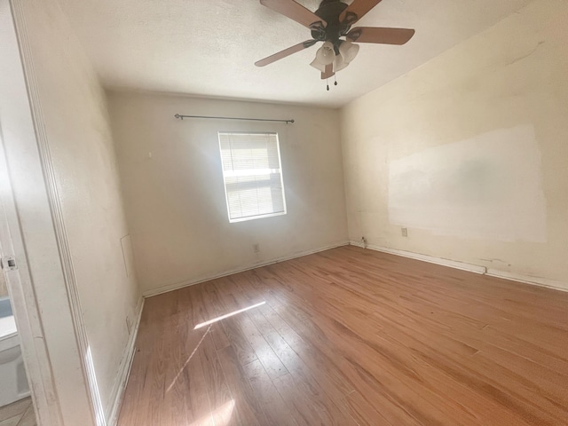 unfurnished room with a ceiling fan, light wood-style flooring, baseboards, and a textured ceiling