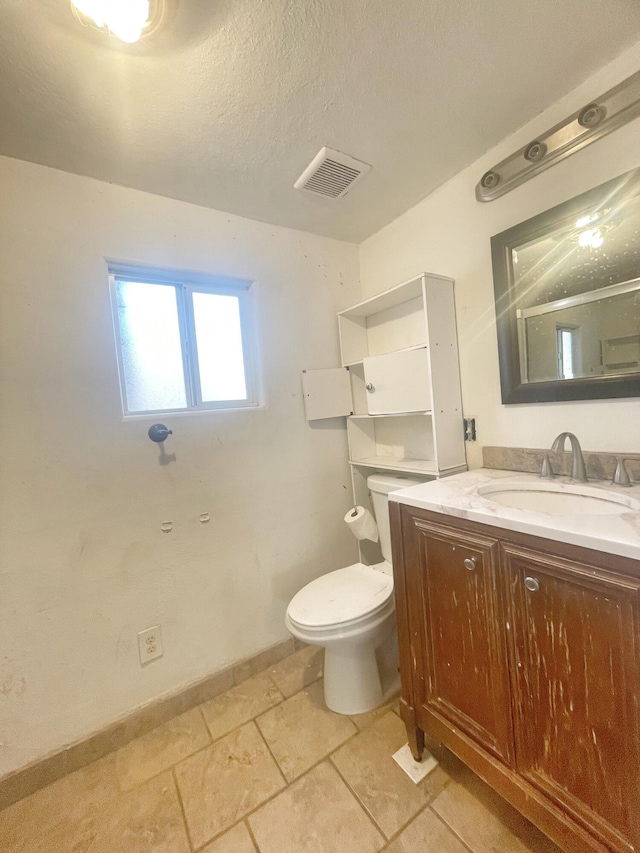 bathroom with baseboards, visible vents, toilet, a textured ceiling, and vanity