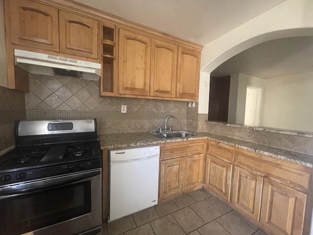 kitchen with dishwasher, light stone counters, stainless steel range with gas stovetop, under cabinet range hood, and a sink